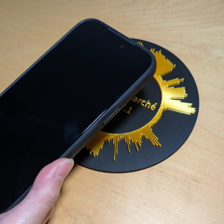 メダル型の声の彫刻の中央にスマホの上部をかざしている様子