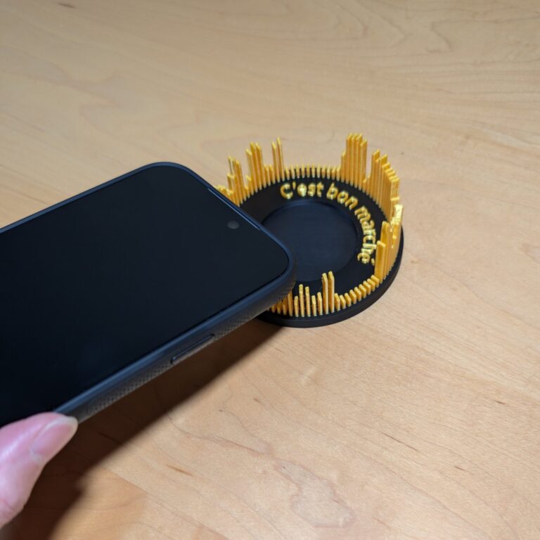 リング型の声の彫刻(指輪皿)の中央にスマホの上部をかざしている様子